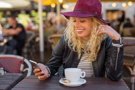 Woman sitting at cafe and using smartphoneの写真素材