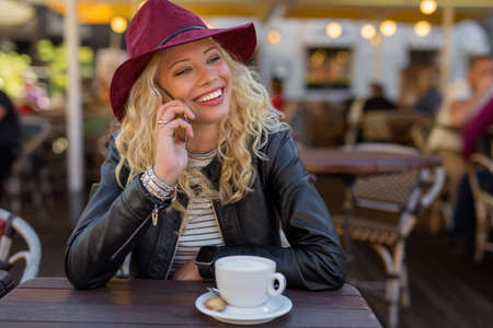Woman having coffee and talking on the phoneの写真素材