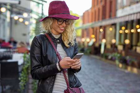 Woman standing on the street and textingの写真素材