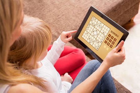 Mother and daughter playing game on tablet computerの写真素材