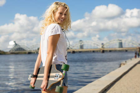 Woman in city environment holding longboardの写真素材