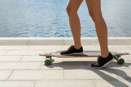 Woman riding longboard by the riverの写真素材