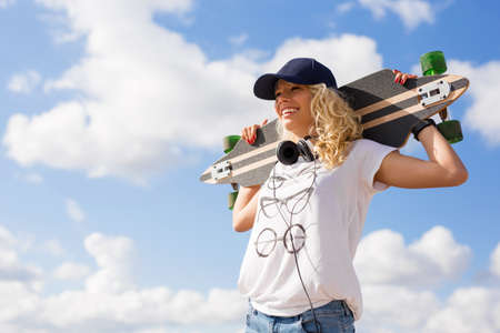 Woman holding longboard behind her headの写真素材