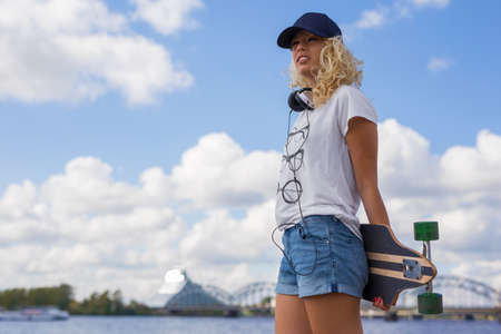 Woman holding longboard behind her backの写真素材