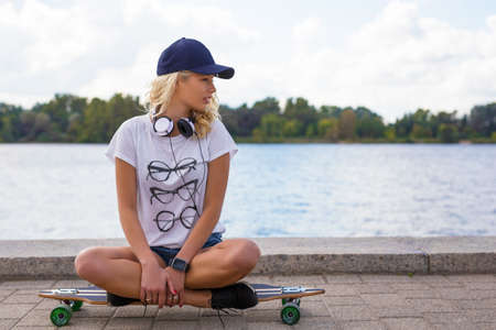 Sporty woman sitting on longboardの写真素材