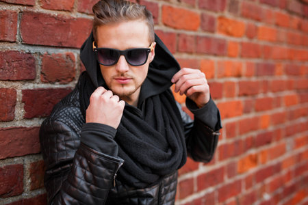 Stylish man in the city standing by the brick wall