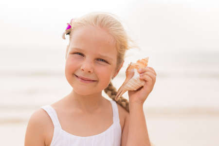 Little girl by the sea listening to seashellの写真素材