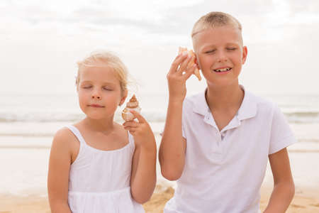 Brother and sister holding a seashellの写真素材