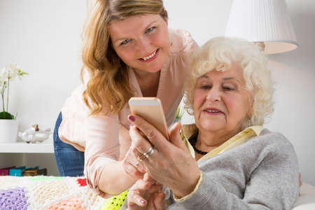 Granddaughter teaching grandma how to use smart phoneの写真素材
