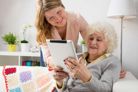 Granddaughter teaching grandma how to use tablet computerの写真素材