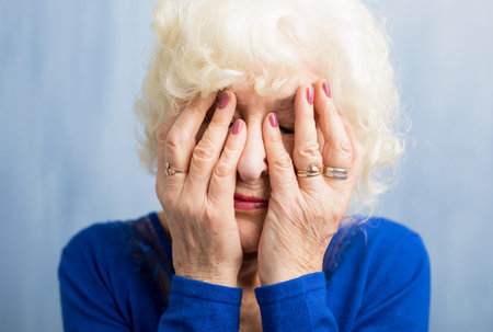 Elderly woman covering her face with both handsの写真素材