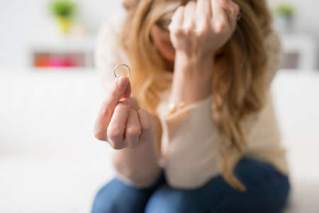 Sad woman holding her wedding ringの写真素材