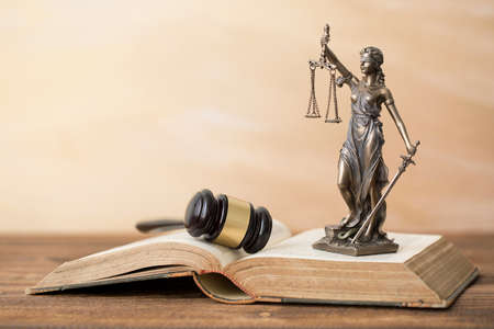 Themis statue on open book and gavel next to itの写真素材