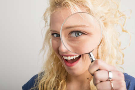 Woman looking through magnifying glassの写真素材