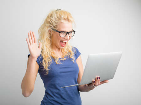 Woman with one hand up looking at computerの写真素材