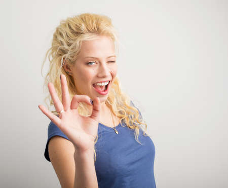 Woman winking and showing ok signの写真素材