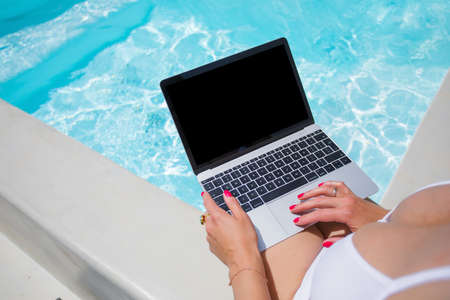 Girl wearing bikini working with laptop by the poolの写真素材