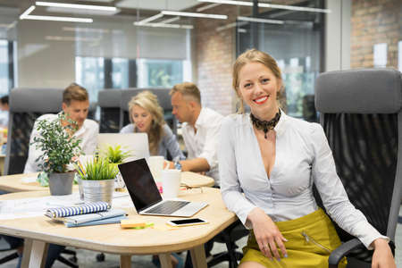 Happy woman sitting with co -workersの写真素材