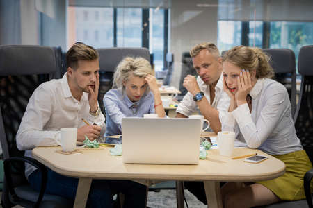 Business team looking at computer with shocked expressionsの写真素材