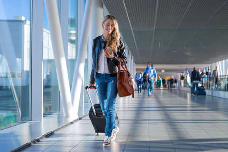 Happy woman travelling and walking in airportの写真素材