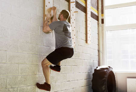 Man exercise on peg board in gymの写真素材