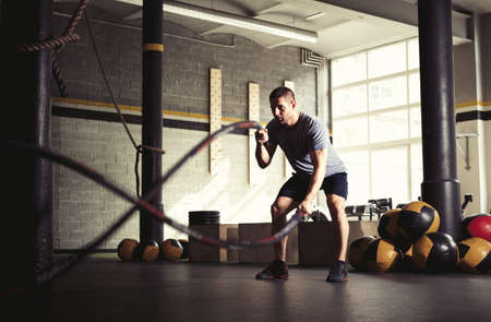 Man with battle ropes in gymの写真素材