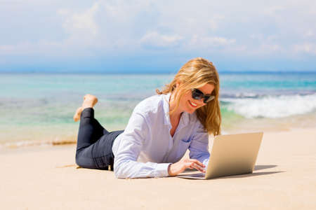 Business woman working with laptop on the beachの写真素材