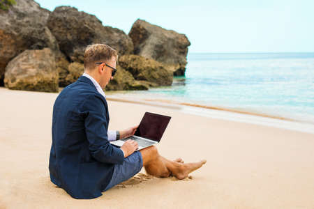Businessman working with laptop on the beachの写真素材