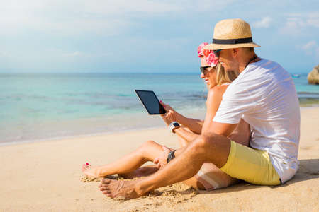Couple using tablet on the beachの写真素材