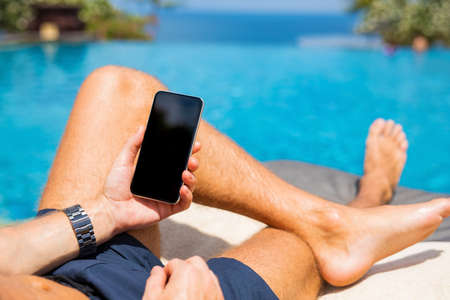 Man with mobile phone by the poolの写真素材