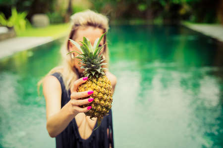 Woman with pineapple in the poolの写真素材