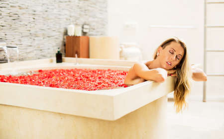 Beautiful woman enjoying romantic flowers bathの写真素材