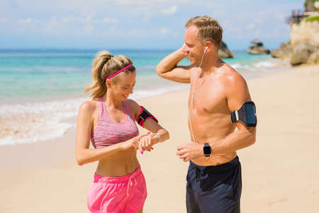 Couple setting devices before workout on the beachの写真素材