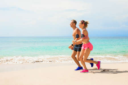 Cheerful couple jogging on the beachの写真素材
