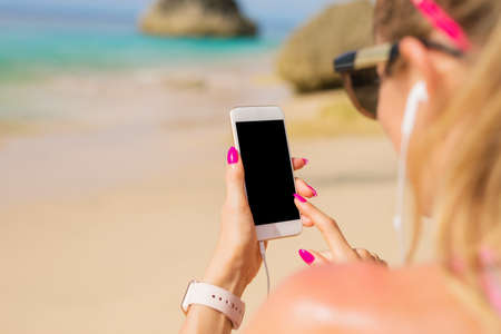 Woman using smartphone on the beachの写真素材