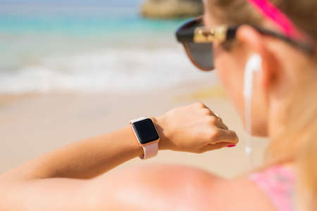 Woman looking at smartwatch on the beachの写真素材