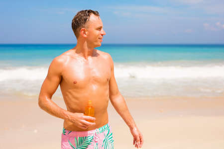 Handsome man with sunscreen lotion on the beachの写真素材