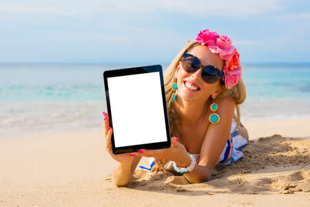Hipster girl showing empty vertical tablet on the beach, mockup for design.の写真素材