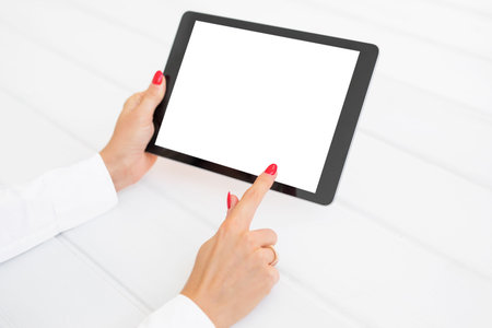 Woman using tablet with white blank screen on white desk