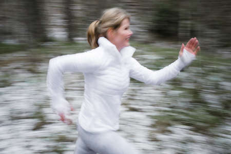 Motion blurred woman running outdoors in winterの写真素材