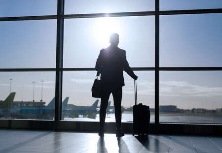 Businessman standing with suitcase in airportの写真素材