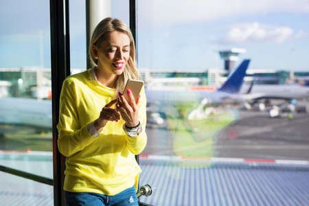 Woman using mobile phone in airportの写真素材
