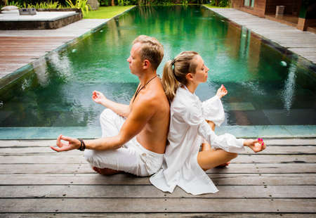 Couple meditate together by the poolの写真素材