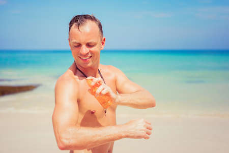 Man applying sun protection spray on his bodyの写真素材