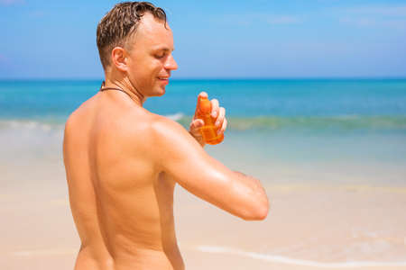 Man using sunscreen product on the beachの写真素材