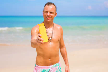 Man holding sunscreen bottle in handの写真素材