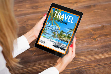 Woman reading travel magazine on tabletの写真素材