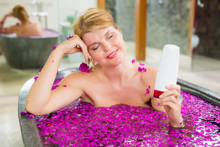 Woman in bath showing blank bottle of body care productの写真素材