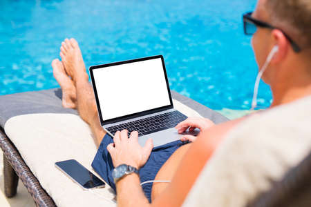 Man using laptop by the pool. Screen mockup.の写真素材