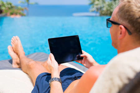 Man holding tablet in hands while on vacation in resort.の写真素材